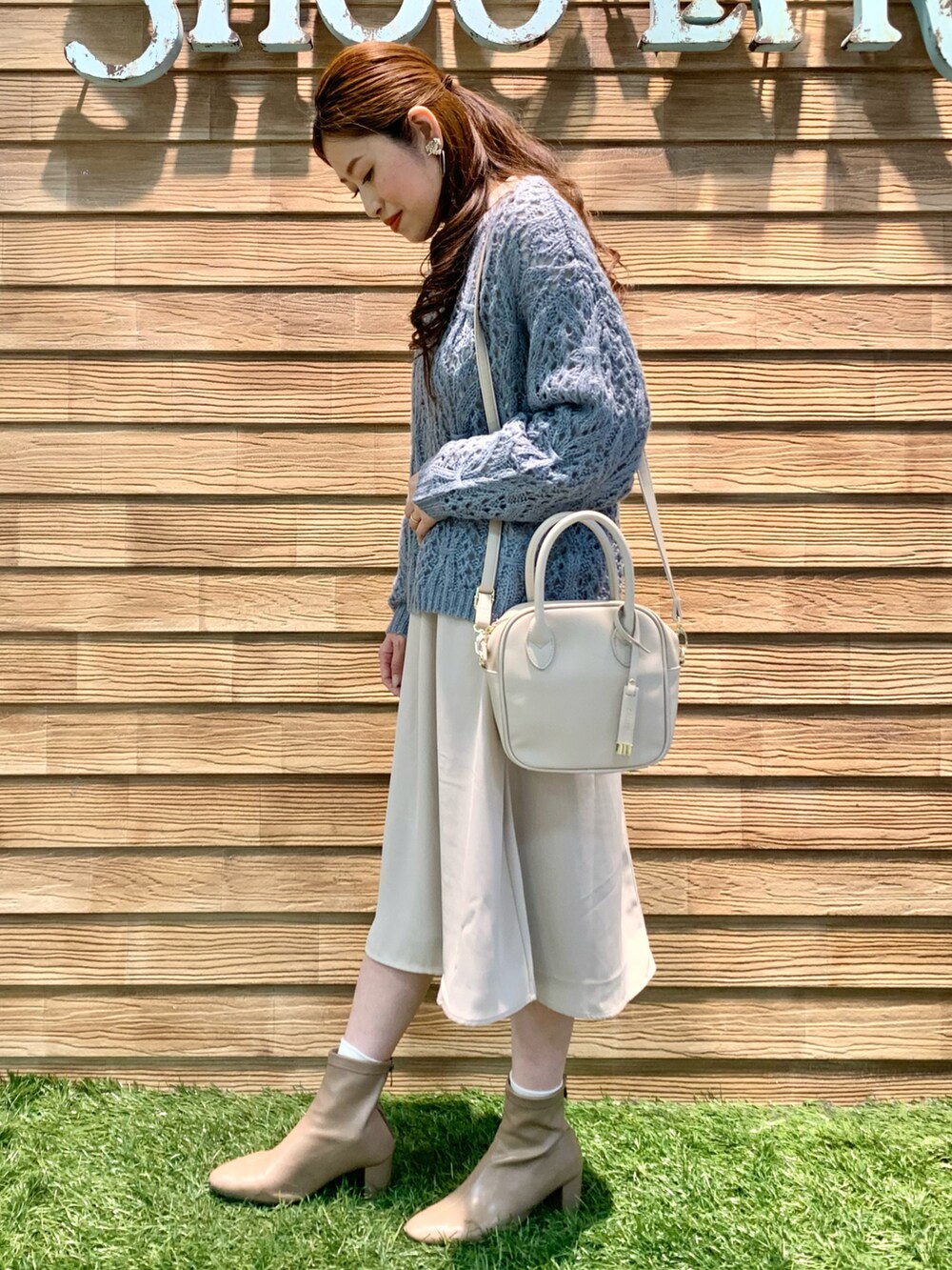 ブルー系のニット/セーター、ベージュ系のワンピース、ホワイト系のショルダーバッグを着用したレディースの冬コーディネートの3枚目の写真