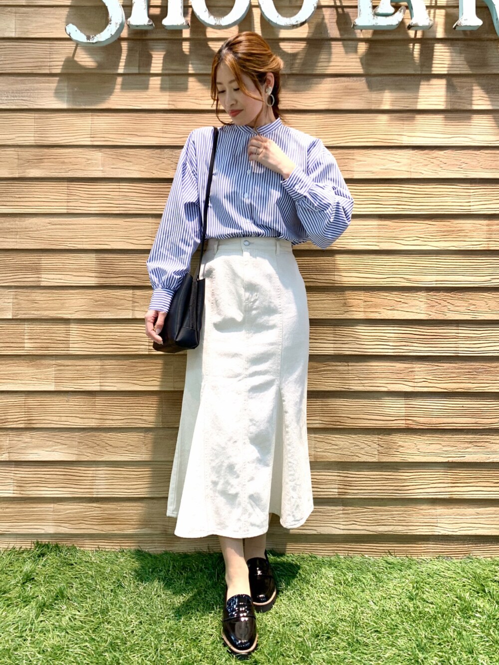 ブルー系のワンピース、ホワイト系のデニムスカート、ブラック系のショルダーバッグを着用したレディースの春コーディネートの2枚目の写真