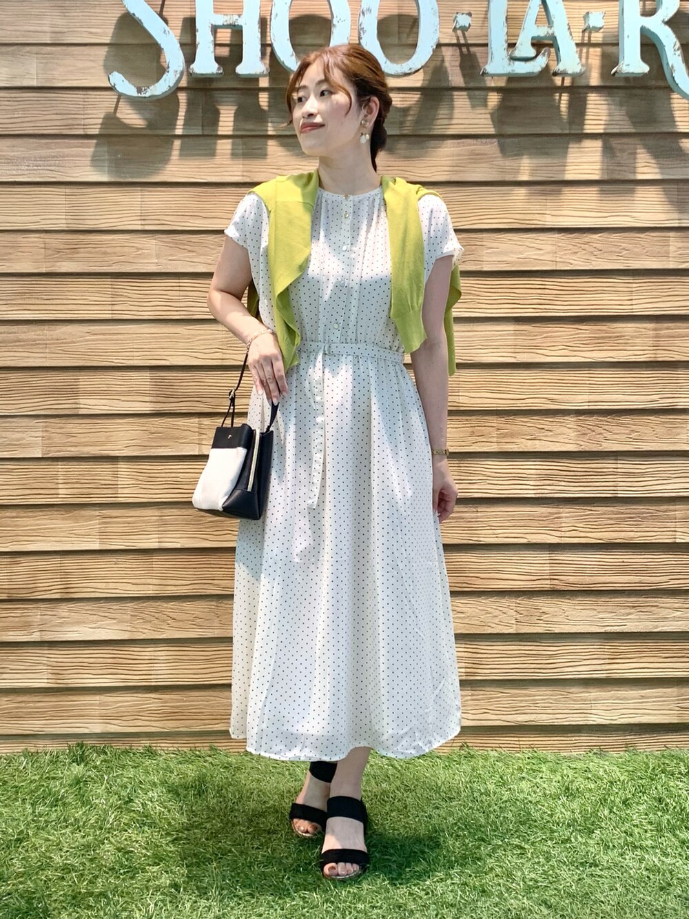 ベージュ系のワンピース、イエロー系のカーディガン/ボレロ、ブラック系のショルダーバッグを着用したレディースの夏コーディネートの3枚目の写真