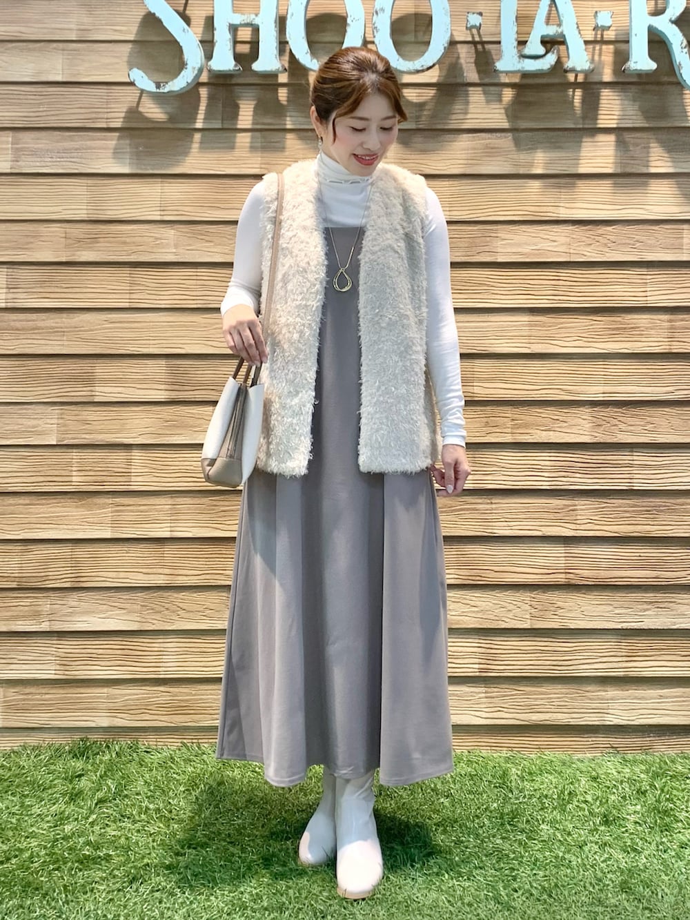 ベージュ系のベスト、ホワイト系のTシャツ/カットソー、イエロー系のワンピースを着用したレディースの春コーディネートの2枚目の写真