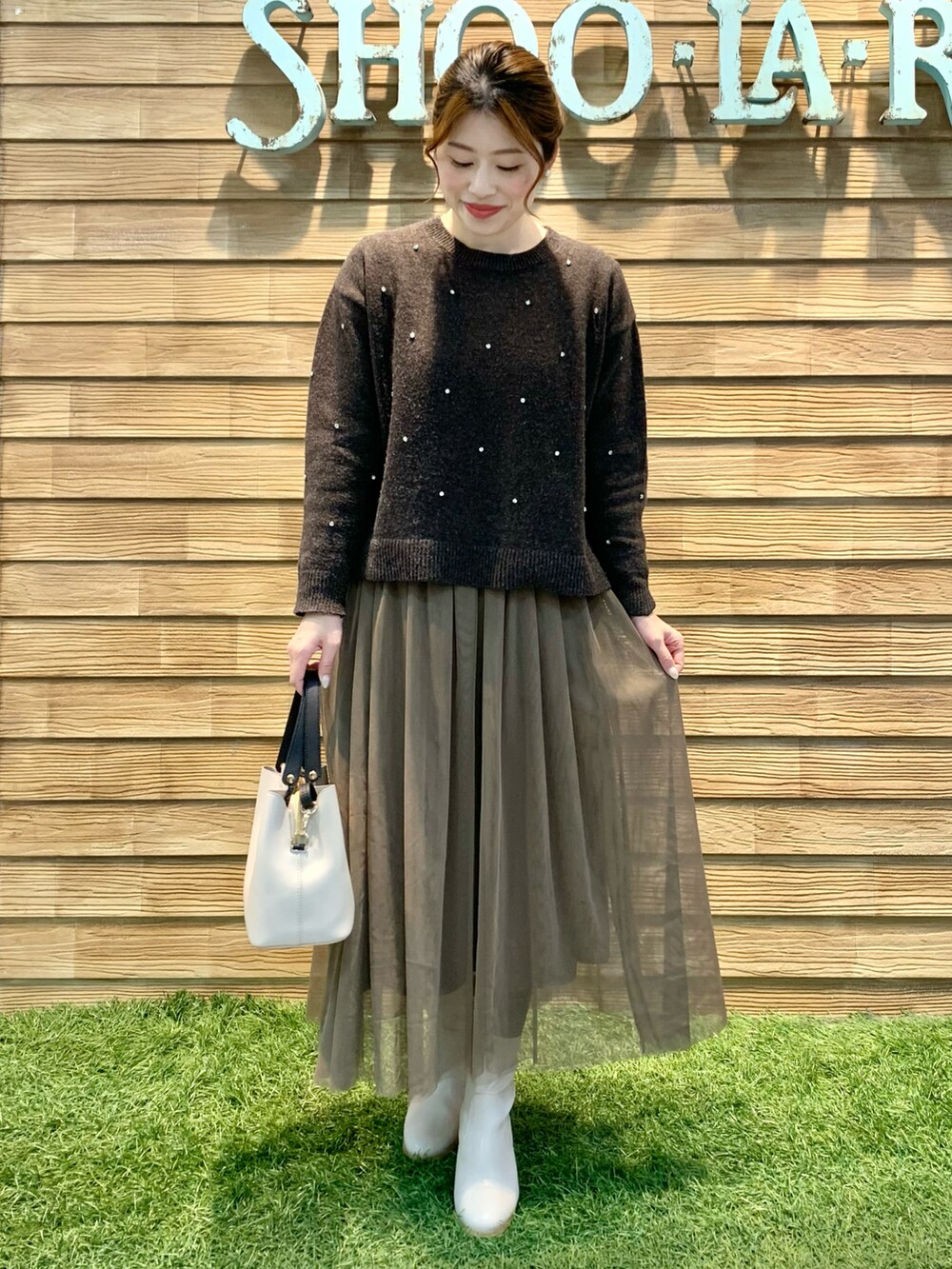 ブラウン系のニット/セーター、ブラウン系のスカート、ベージュ系のトートバッグを着用したレディースの冬コーディネートの2枚目の写真