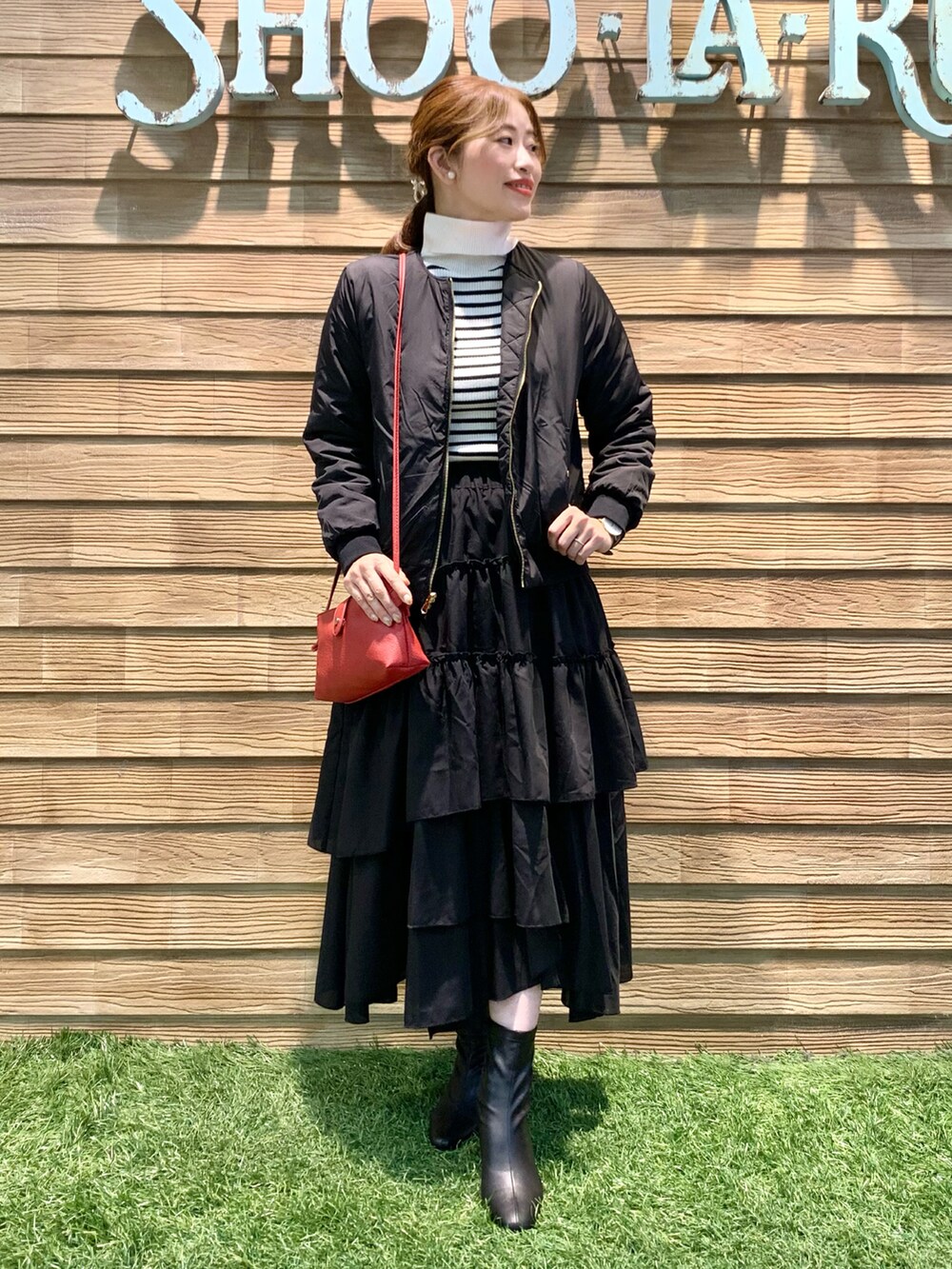 ブラック系のブルゾン、ホワイト系のニット/セーター、ブラック系のスカートを着用したレディースの秋コーディネートの2枚目の写真