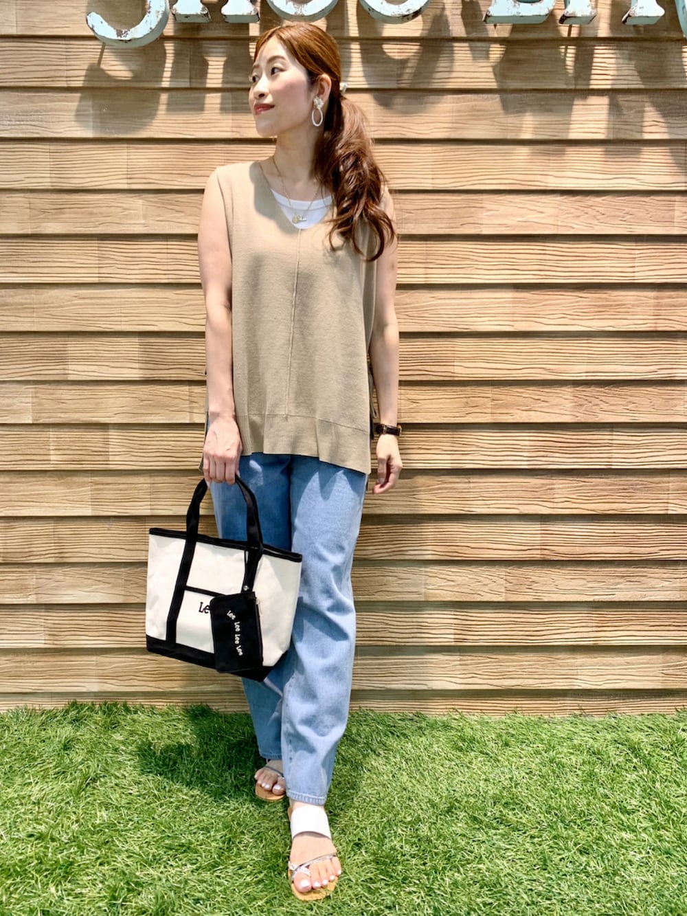 ベージュ系のベスト、ブルー系のデニムパンツ、ブラック系のトートバッグを着用したレディースの夏コーディネートの3枚目の写真