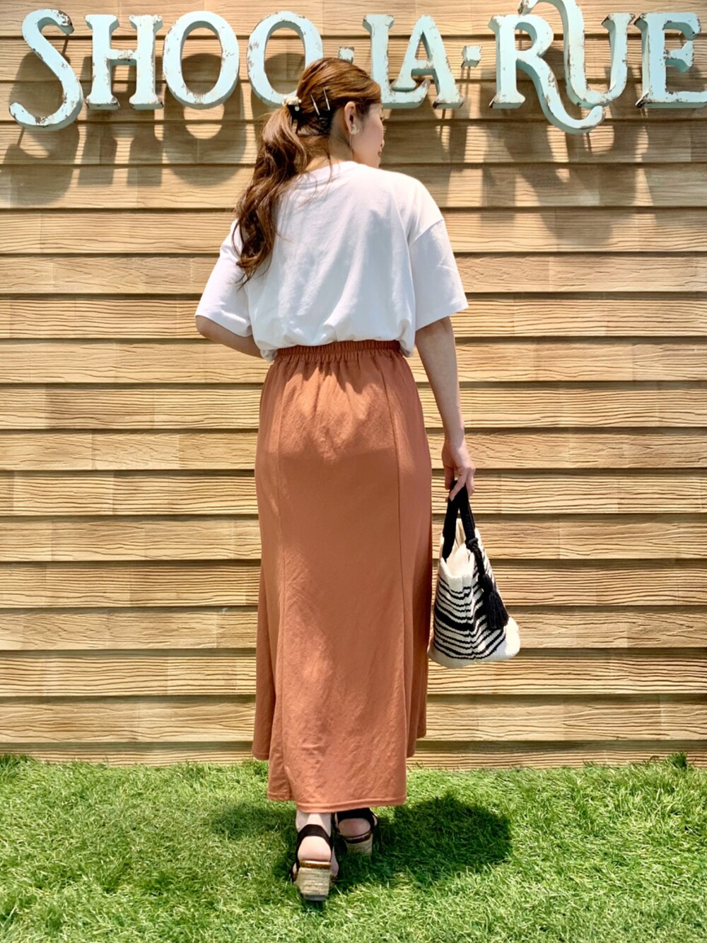ホワイト系のTシャツ/カットソー、オレンジ系のスカート、ブラック系のトートバッグを着用したレディースの夏コーディネートの5枚目の写真