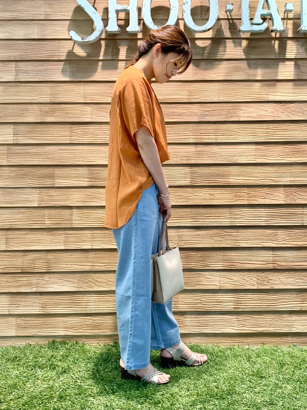オレンジ系のシャツ/ブラウス、ブルー系のデニムパンツ、ベージュ系のショルダーバッグを着用したレディースの秋コーディネートの4枚目の写真