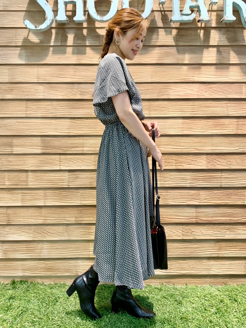 ブラック系のワンピース、ブラック系のショルダーバッグ、ブラック系のブーツを着用したレディースの秋コーディネートの4枚目の写真