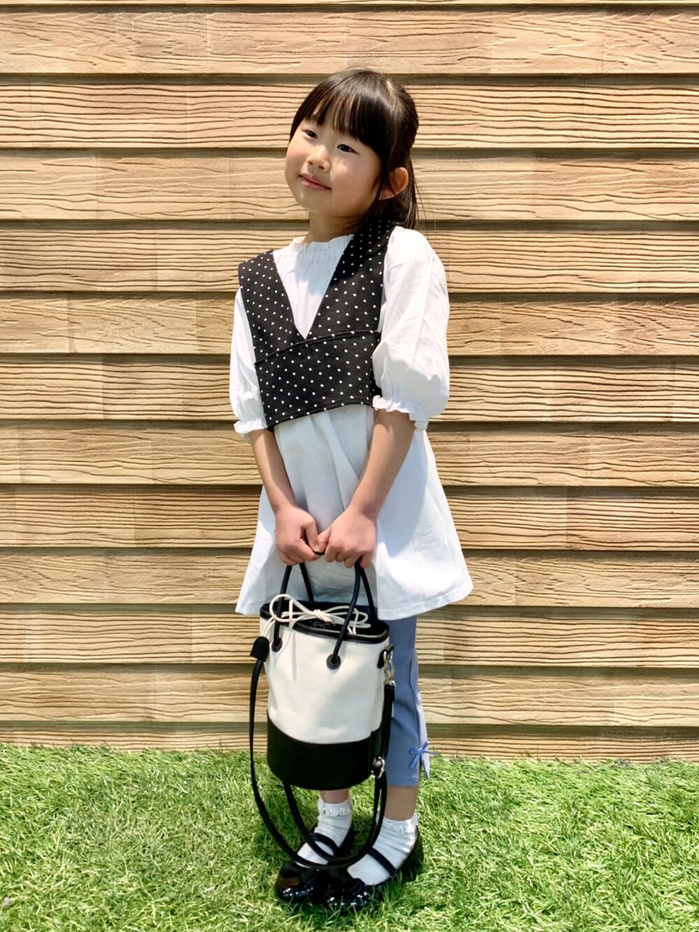 ブラック系のワンピース、ブルー系のその他パンツ、ブラック系のハンドバッグを着用したキッズの春コーディネートの2枚目の写真
