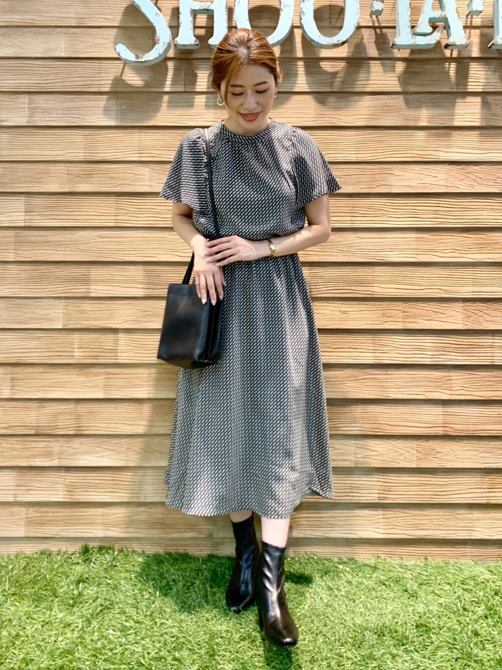 ブラック系のワンピース、ブラック系のショルダーバッグ、ブラック系のブーツを着用したレディースの秋コーディネートの2枚目の写真