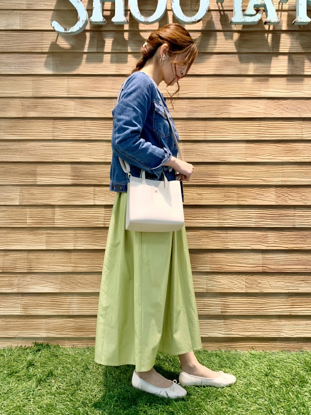 ブルー系のデニムジャケット、ホワイト系のニット/セーター、イエロー系のスカートを着用したレディースの春コーディネートの4枚目の写真