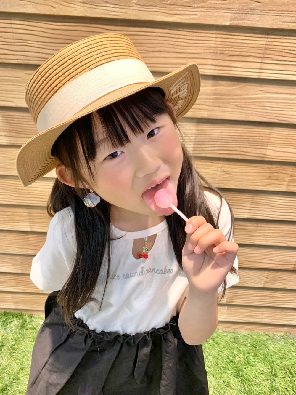 ブラック系のワンピース、ピンク系のトートバッグ、ベージュ系のハットを着用したキッズの秋コーディネートの5枚目の写真