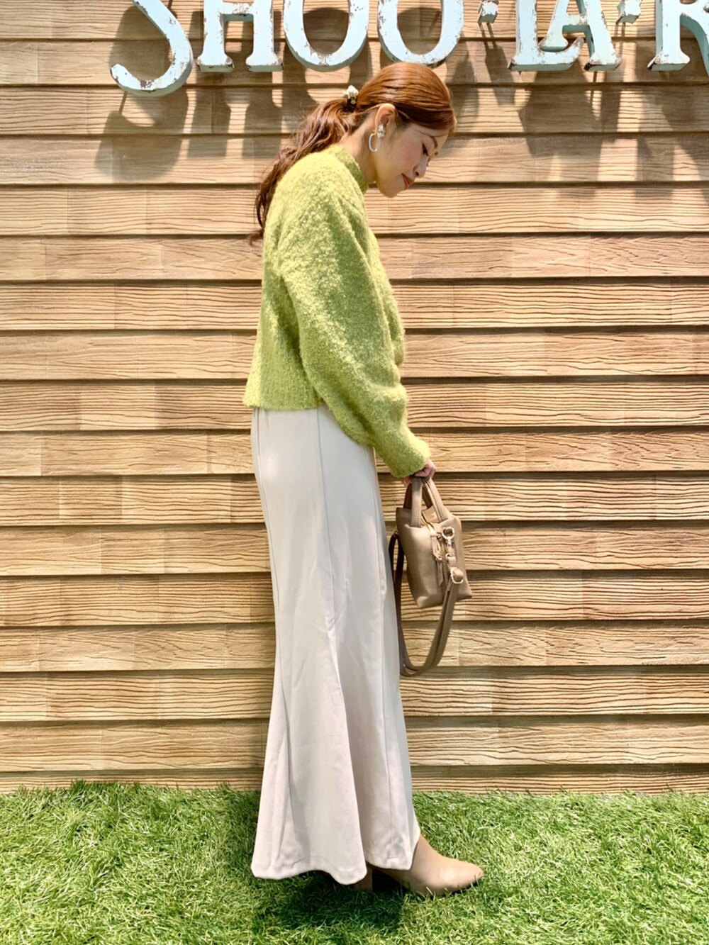 グリーン系のニット/セーター、ホワイト系のスカート、グレー系のショルダーバッグを着用したレディースの秋コーディネートの4枚目の写真