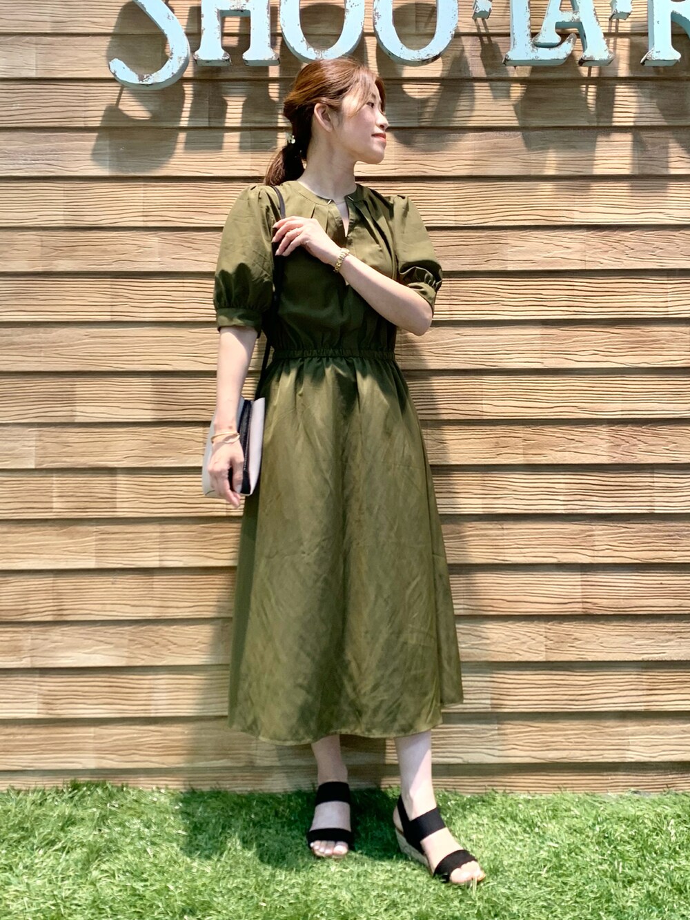 グリーン系のワンピース、グレー系のショルダーバッグ、ブラック系のサンダルを着用したレディースの秋コーディネートの3枚目の写真