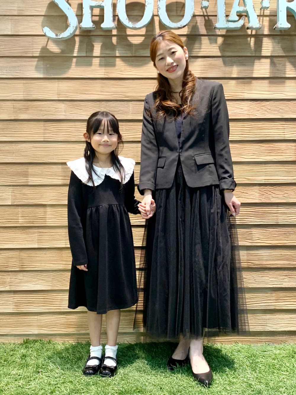 ブラック系のワンピース、ブラック系のドレスシューズ、ブラウン系のラッピングキットを着用したキッズの春コーディネートの5枚目の写真