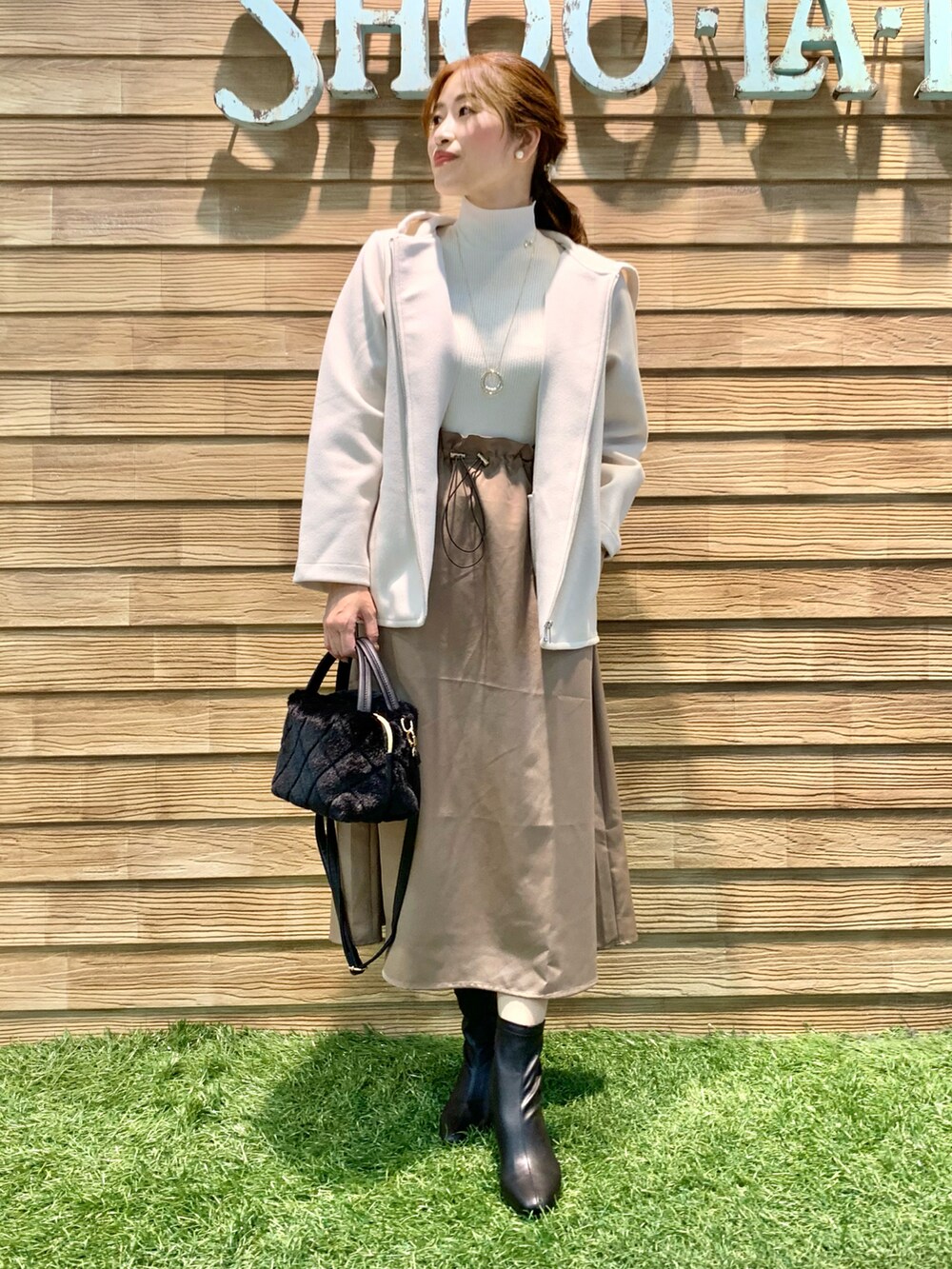 ホワイト系のブルゾン、ベージュ系のワンピース、ブラック系のショルダーバッグを着用したレディースの春コーディネートの5枚目の写真