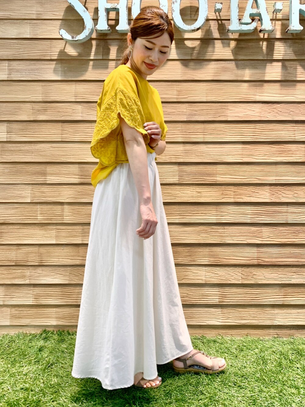 イエロー系のシャツ/ブラウス、ホワイト系のスカート、ベージュ系のサンダルを着用したレディースの夏コーディネートの5枚目の写真