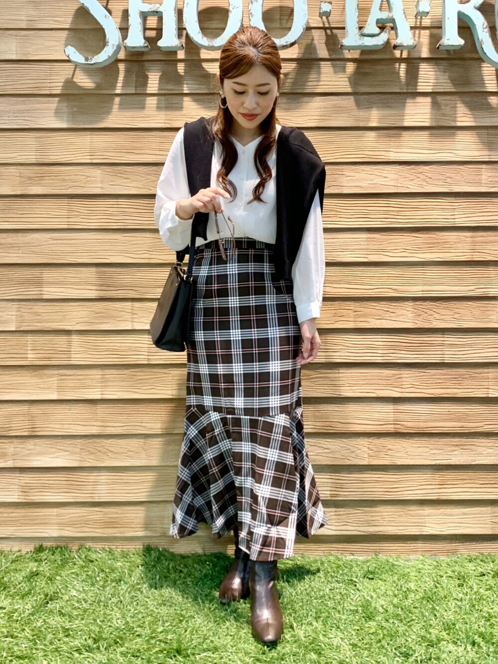 ブラック系のカーディガン/ボレロ、ホワイト系のシャツ/ブラウス、ブラウン系のスカートを着用したレディースの秋コーディネートの2枚目の写真