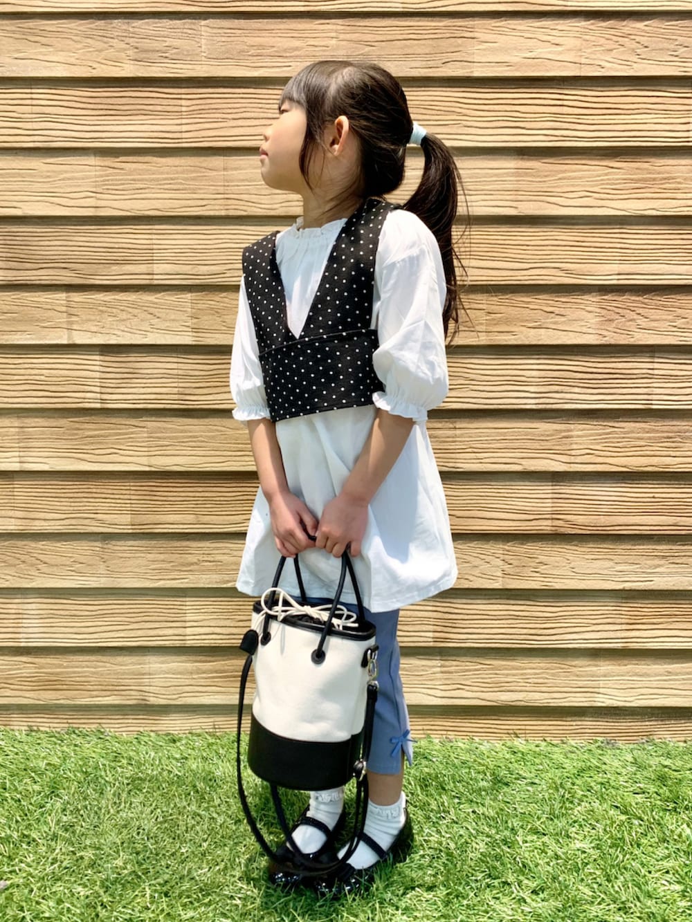 ブラック系のワンピース、ブルー系のその他パンツ、ブラック系のハンドバッグを着用したキッズの春コーディネートの4枚目の写真
