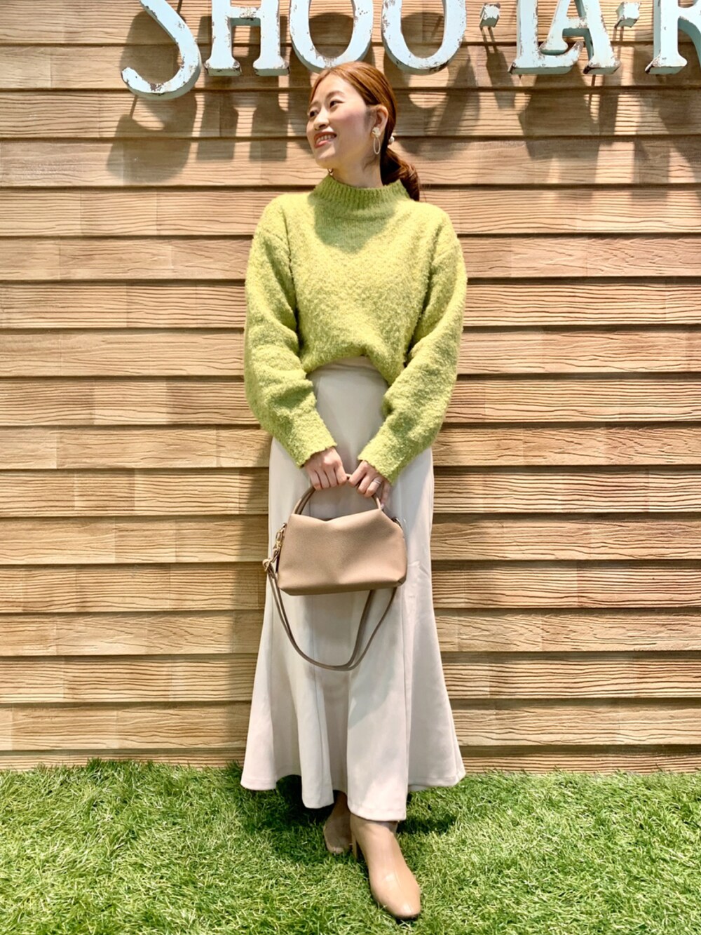 グリーン系のニット/セーター、ホワイト系のスカート、グレー系のショルダーバッグを着用したレディースの秋コーディネートの2枚目の写真