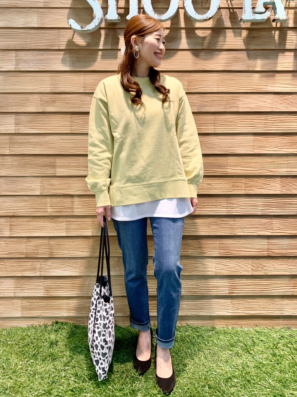 イエロー系のスウェット、ベージュ系のTシャツ/カットソー、ブルー系のデニムパンツを着用したレディースの春コーディネートの2枚目の写真