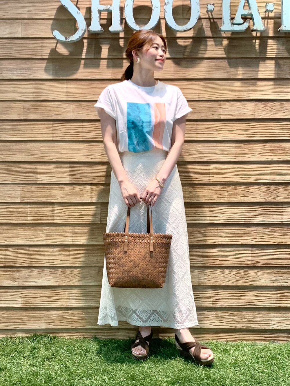 ホワイト系のTシャツ/カットソー、ホワイト系のスカート、ブラウン系のトートバッグを着用したレディースの夏コーディネートの2枚目の写真