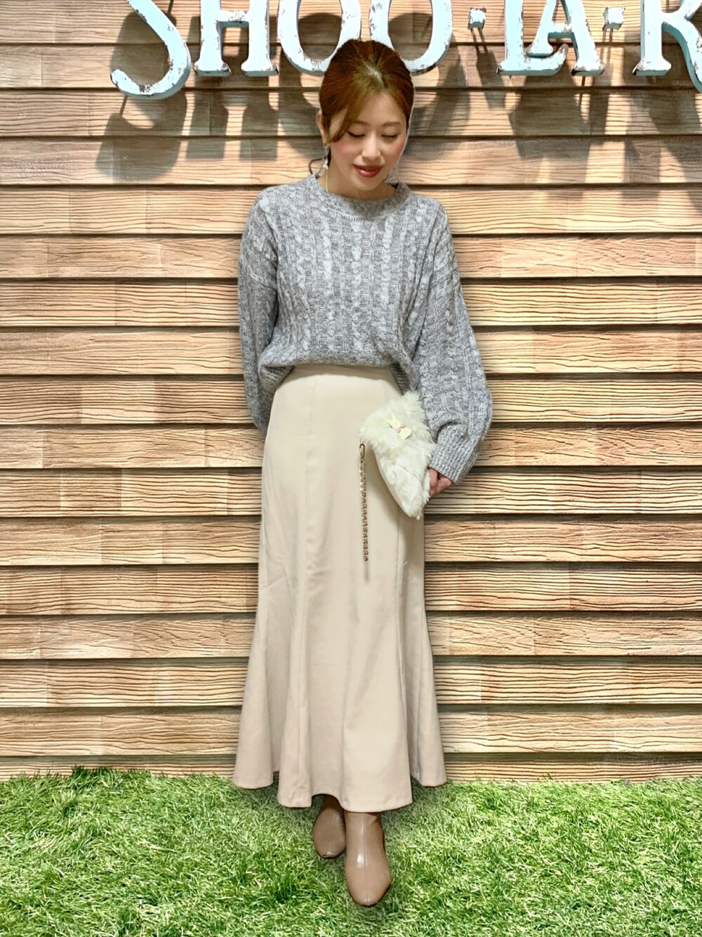 グレー系のニット/セーター、ホワイト系のスカート、ベージュ系のブーツを着用したレディースの冬コーディネートの3枚目の写真