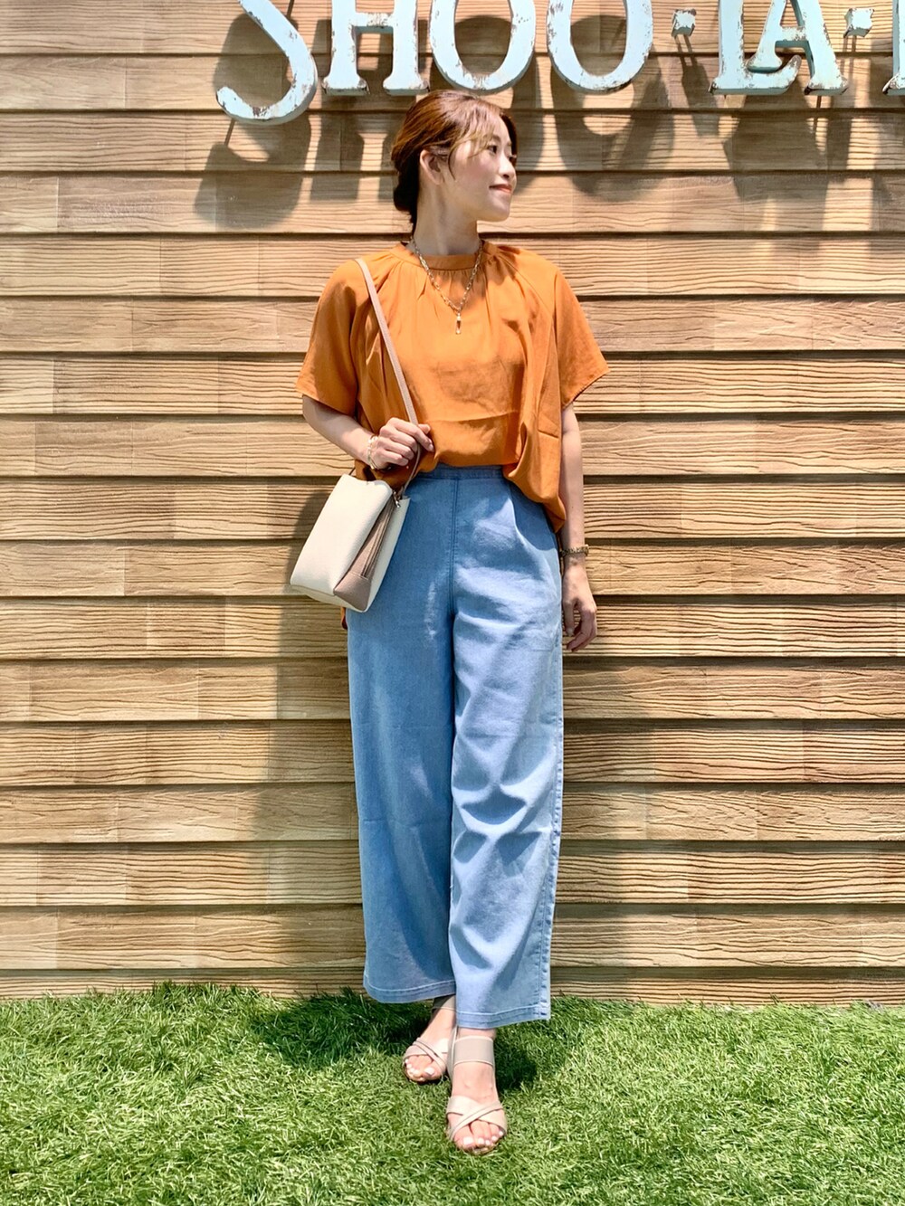 オレンジ系のシャツ/ブラウス、ブルー系のデニムパンツ、ベージュ系のショルダーバッグを着用したレディースの秋コーディネートの2枚目の写真
