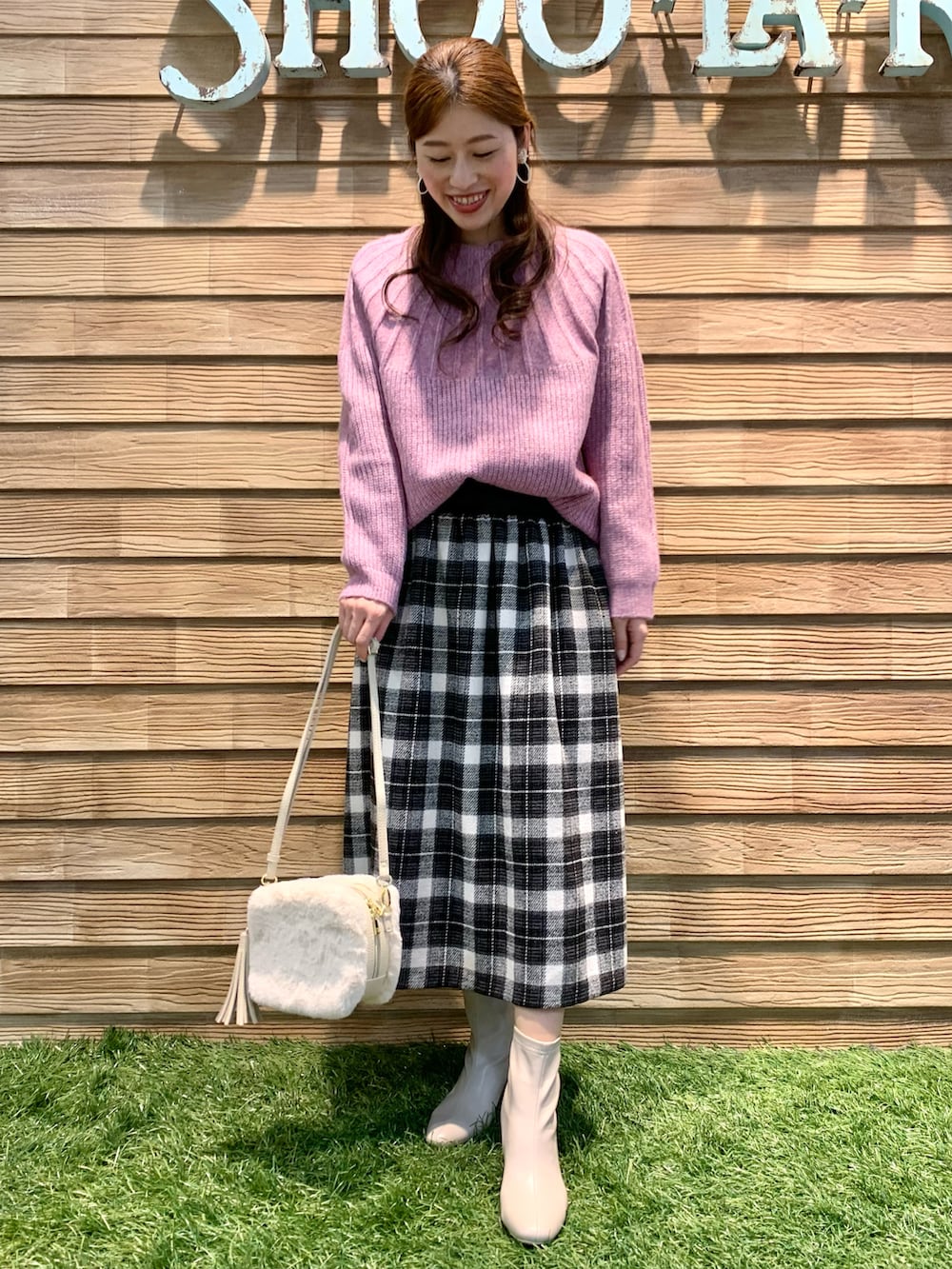 ピンク系のニット/セーター、グレー系のスカート、ホワイト系のショルダーバッグを着用したレディースの冬コーディネートの4枚目の写真