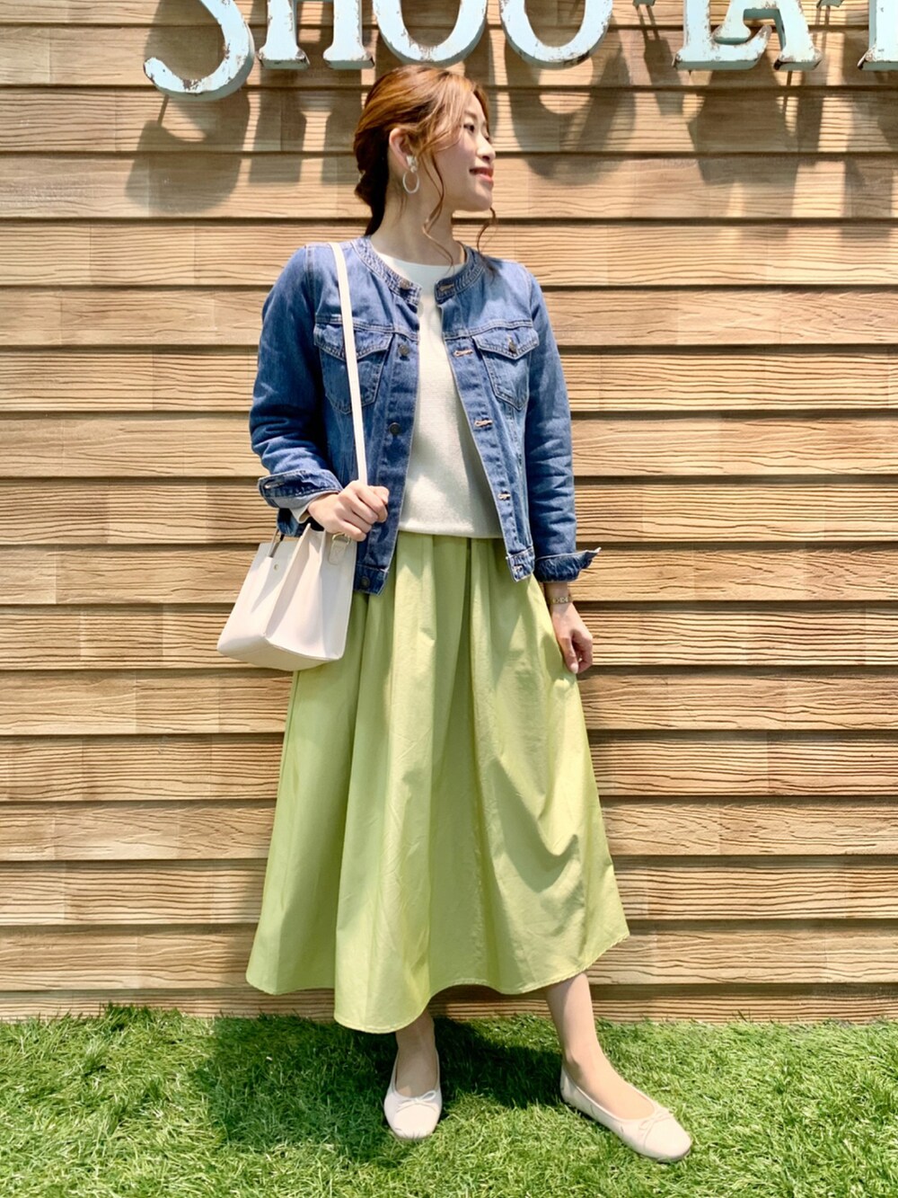 ブルー系のデニムジャケット、ホワイト系のニット/セーター、イエロー系のスカートを着用したレディースの春コーディネートの3枚目の写真