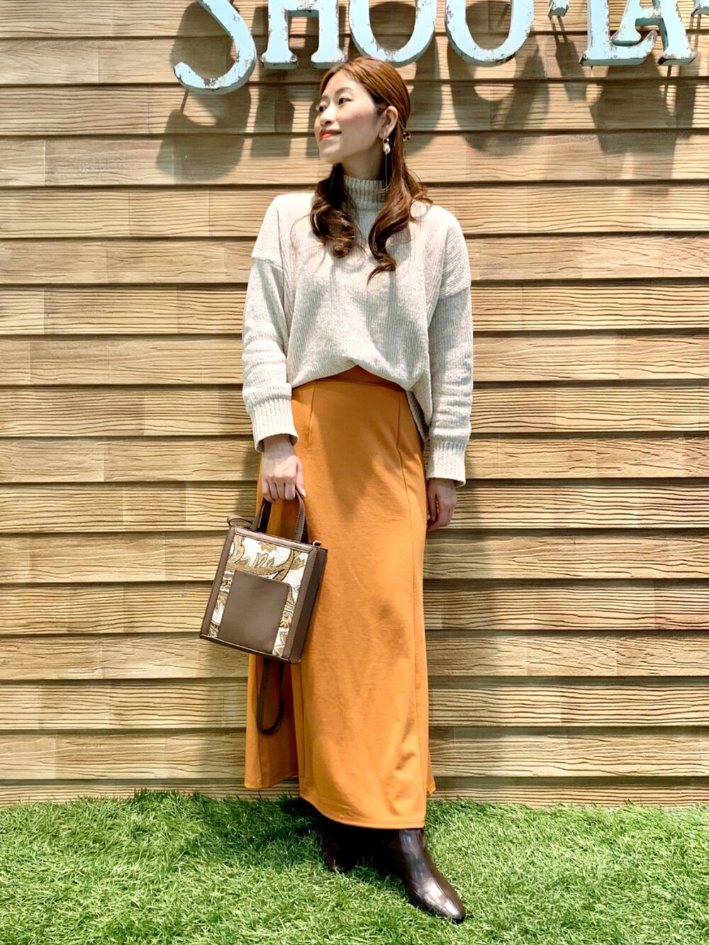 ホワイト系のニット/セーター、オレンジ系のスカート、ブラウン系のショルダーバッグを着用したレディースの冬コーディネートの2枚目の写真