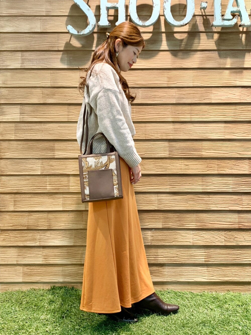 ホワイト系のニット/セーター、オレンジ系のスカート、ブラウン系のショルダーバッグを着用したレディースの冬コーディネートの4枚目の写真