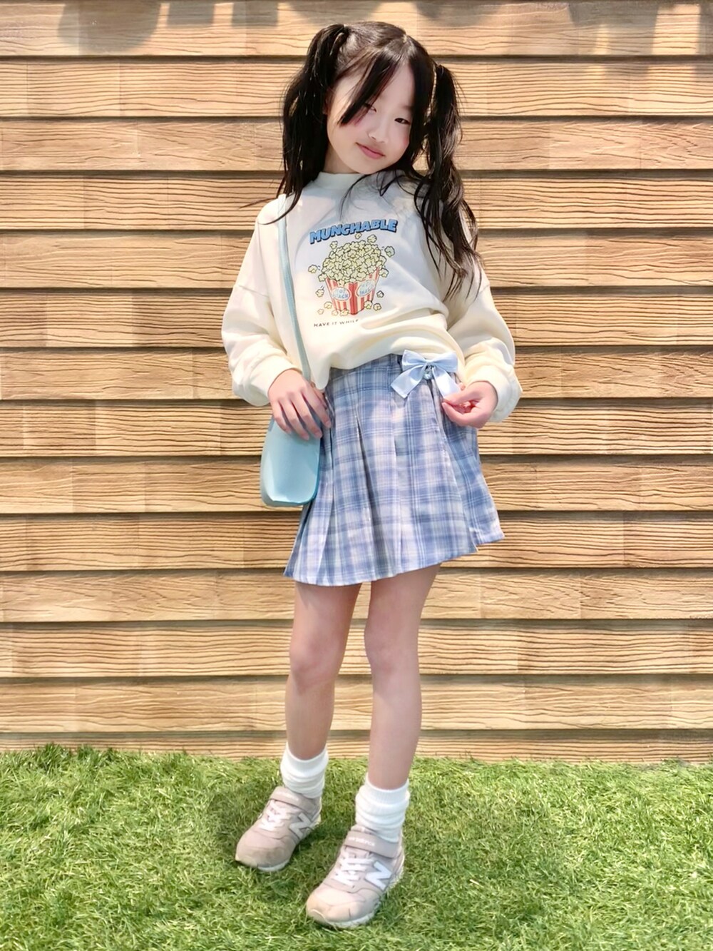 ホワイト系のスウェット、ブルー系のスカート、グリーン系のショルダーバッグを着用したキッズの夏コーディネートの4枚目の写真