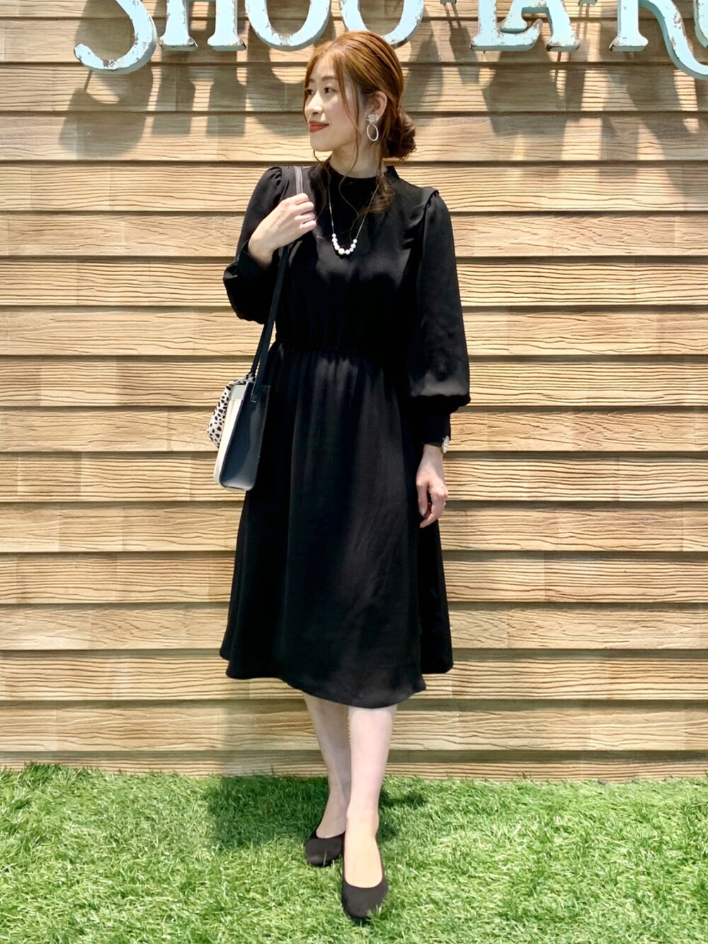 ブラック系のワンピース、ブラック系のショルダーバッグ、ブラック系のパンプスを着用したレディースの冬コーディネートの2枚目の写真