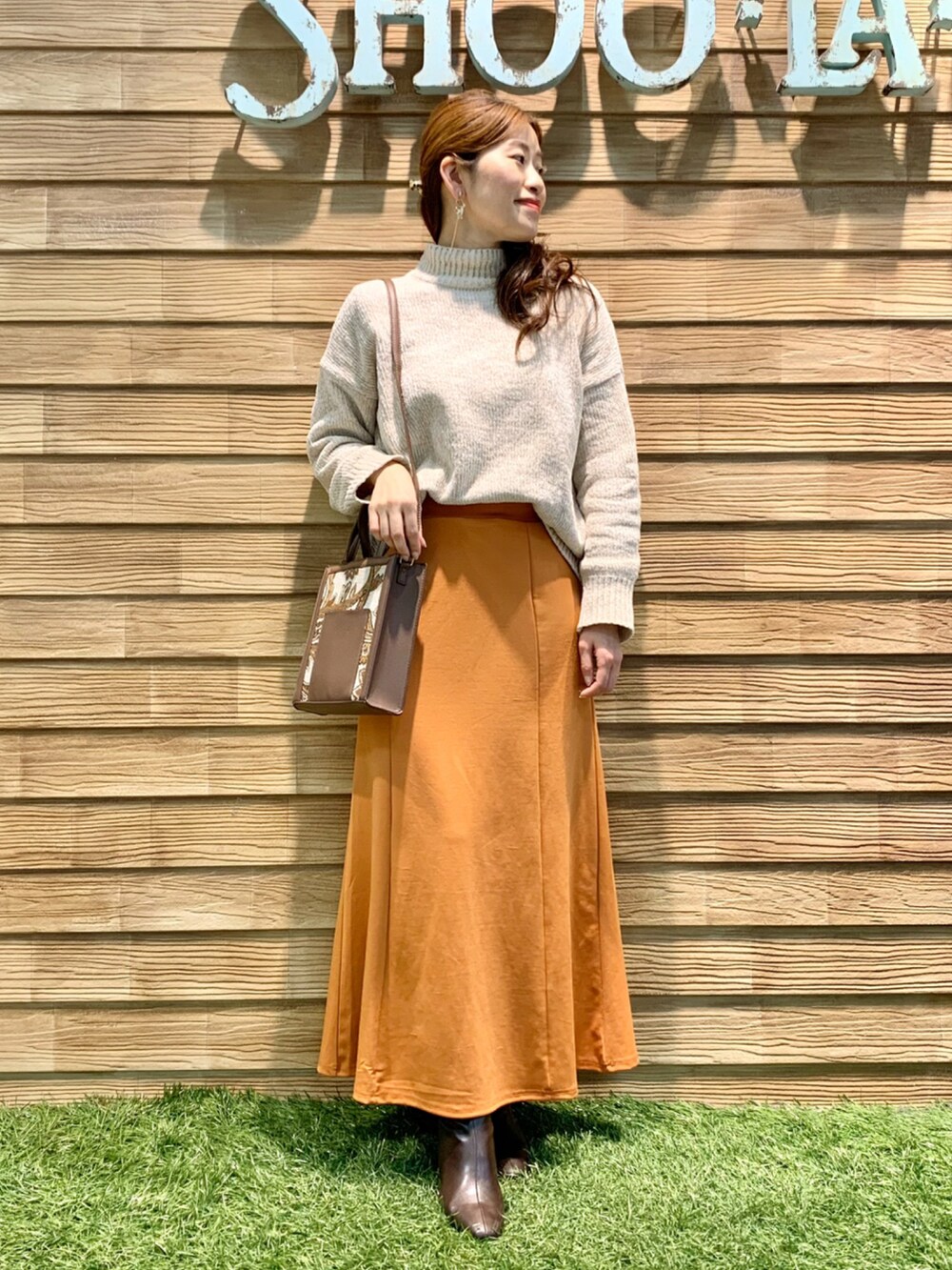 ホワイト系のニット/セーター、オレンジ系のスカート、ブラウン系のショルダーバッグを着用したレディースの冬コーディネートの3枚目の写真