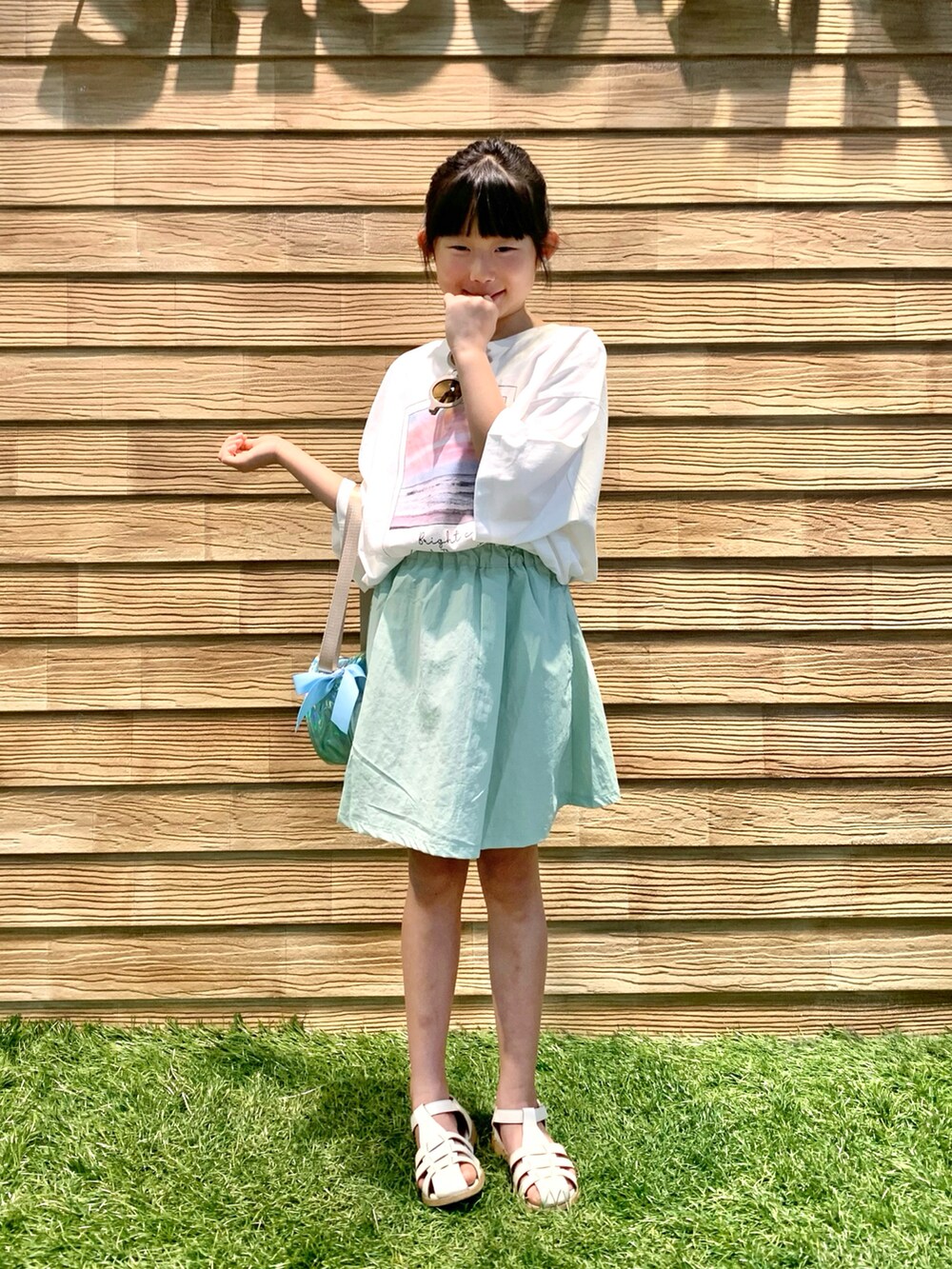 ホワイト系のTシャツ/カットソー、グリーン系のスカート、ブルー系のショルダーバッグを着用したキッズの秋コーディネートの2枚目の写真