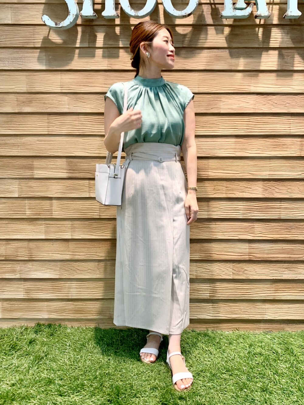 グリーン系のシャツ/ブラウス、ベージュ系のスカート、ホワイト系のショルダーバッグを着用したレディースの夏コーディネートの2枚目の写真