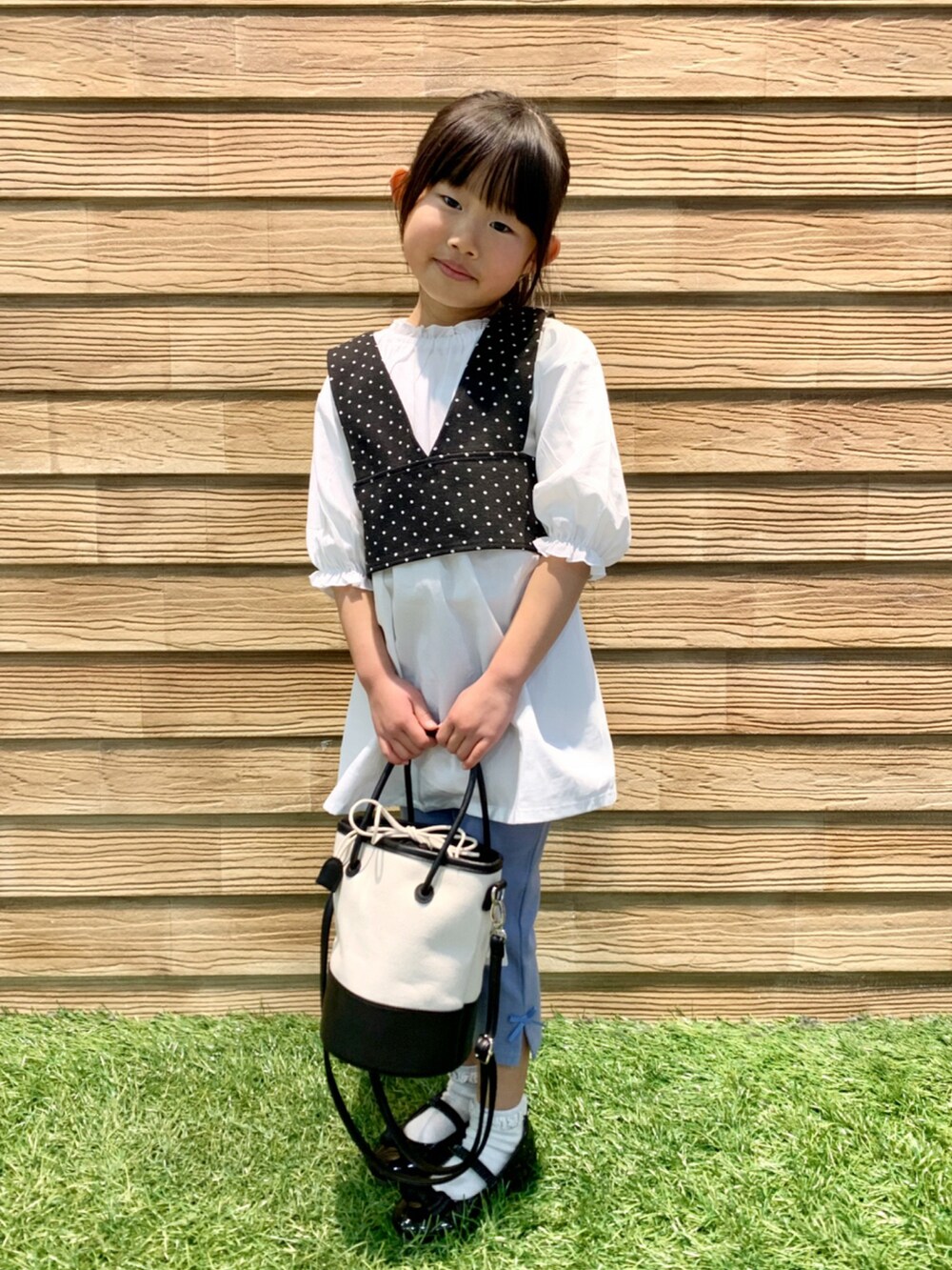 ブラック系のワンピース、ブルー系のその他パンツ、ブラック系のハンドバッグを着用したキッズの春コーディネートの3枚目の写真