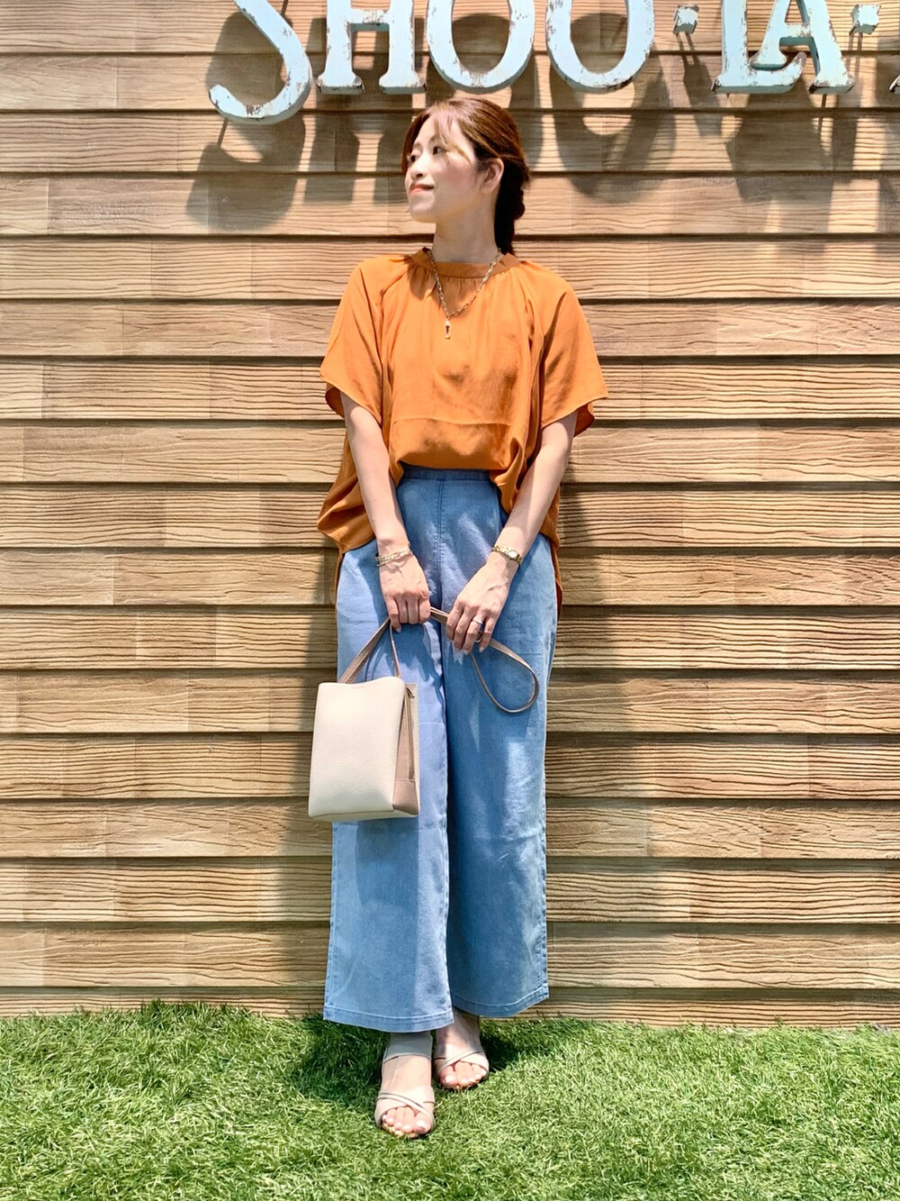 オレンジ系のシャツ/ブラウス、ブルー系のデニムパンツ、ベージュ系のショルダーバッグを着用したレディースの秋コーディネートの3枚目の写真