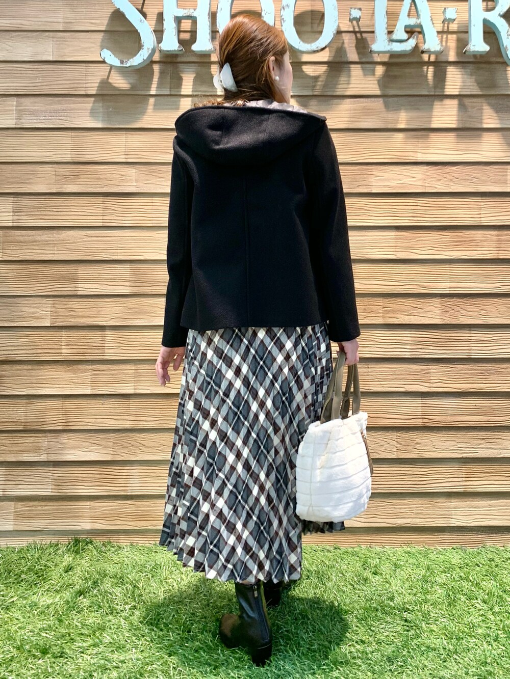 ブラック系のその他アウター、ホワイト系のニット/セーター、レッド系のスカートを着用したレディースの冬コーディネートの4枚目の写真