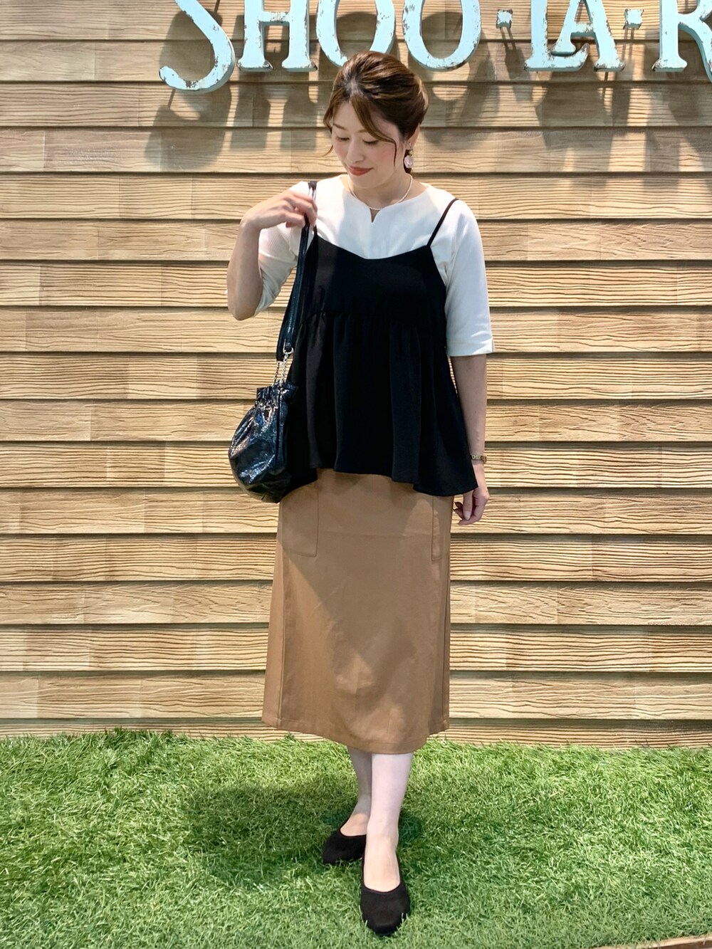 ブラック系のタンクトップ、ホワイト系のTシャツ/カットソー、イエロー系のスカートを着用したレディースの秋コーディネートの3枚目の写真