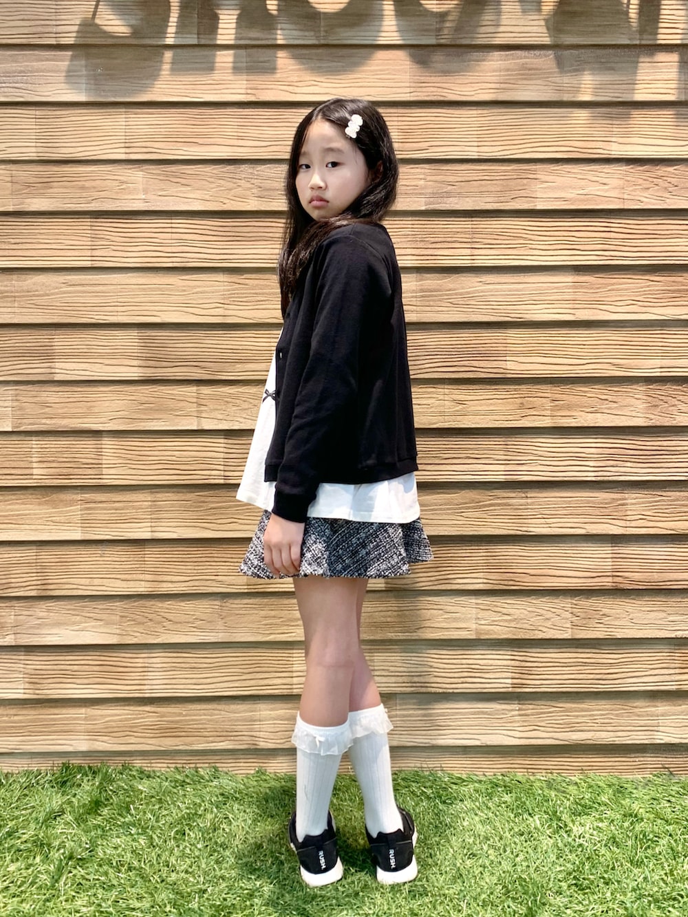 ブラック系のカーディガン/ボレロ、ホワイト系のTシャツ/カットソー、ブラック系のスカートを着用したキッズの春コーディネートの3枚目の写真