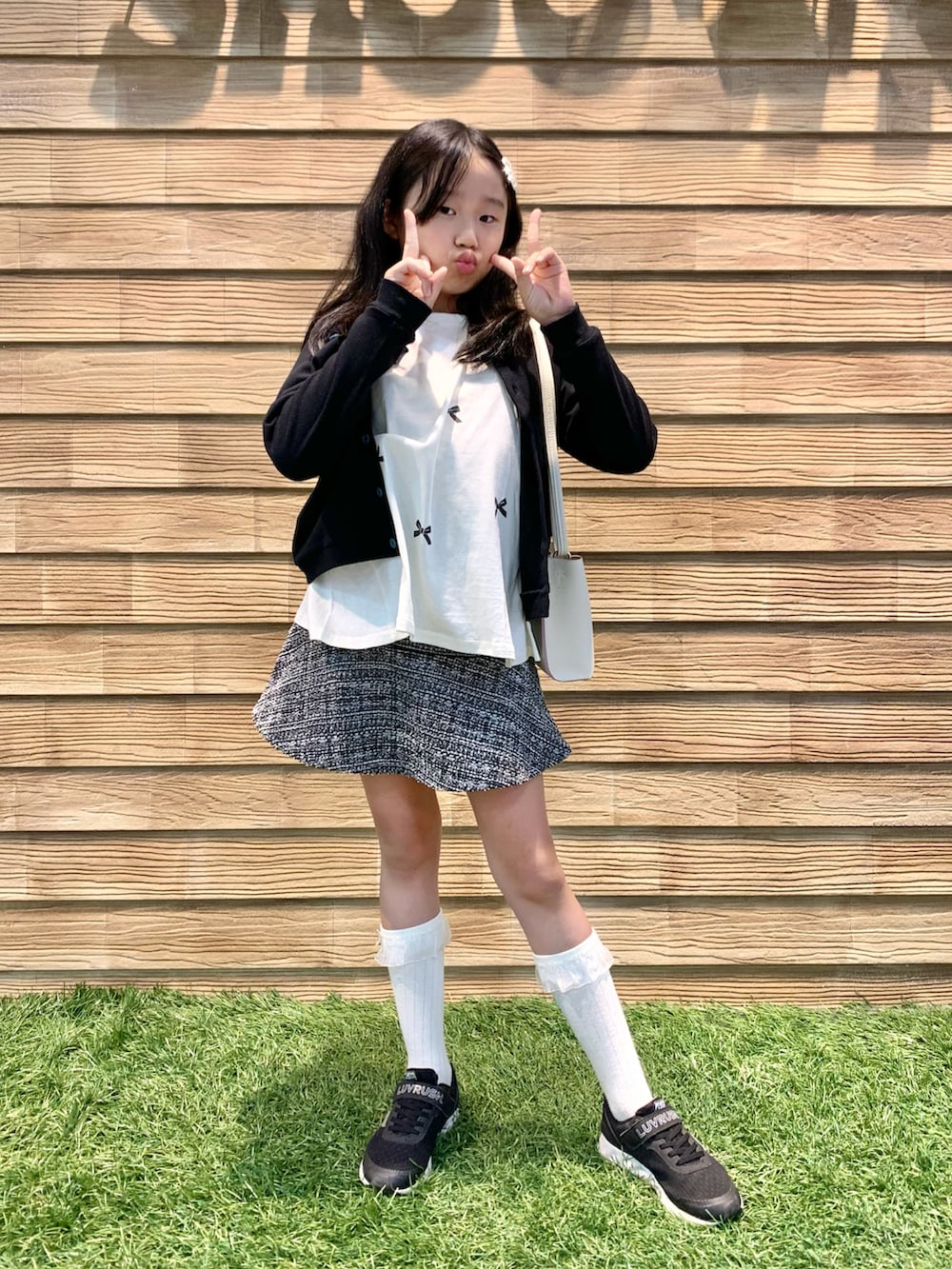 ブラック系のカーディガン/ボレロ、ホワイト系のTシャツ/カットソー、ブラック系のスカートを着用したキッズの春コーディネートの2枚目の写真