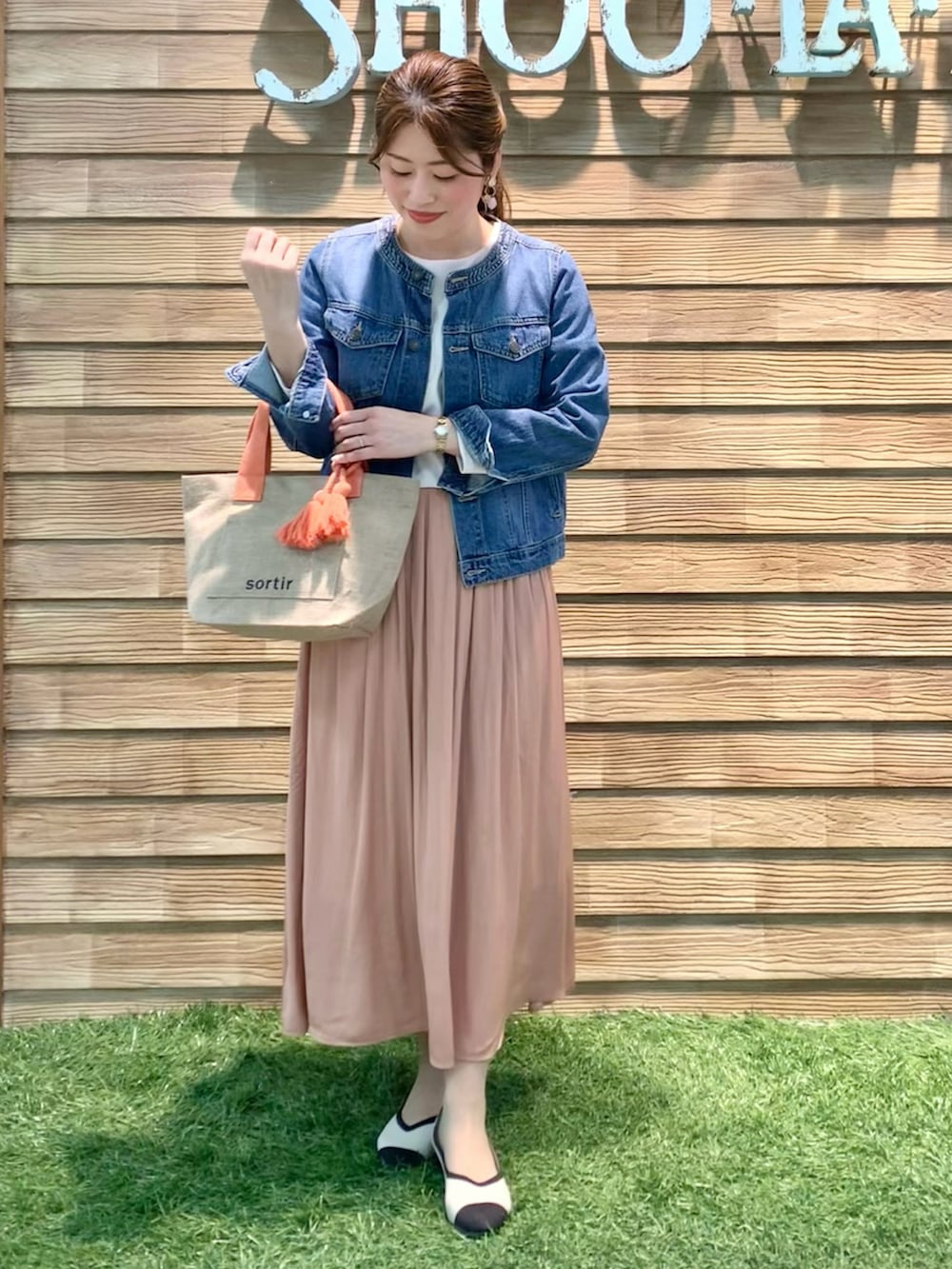 ブルー系のデニムジャケット、ベージュ系のTシャツ/カットソー、オレンジ系のスカートを着用したレディースの春コーディネートの3枚目の写真