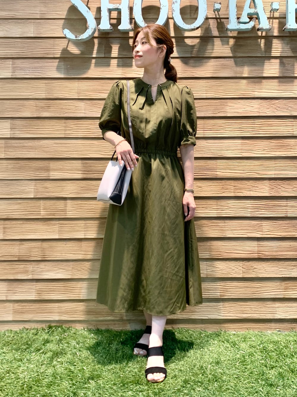 グリーン系のワンピース、グレー系のショルダーバッグ、ブラック系のサンダルを着用したレディースの秋コーディネートの2枚目の写真