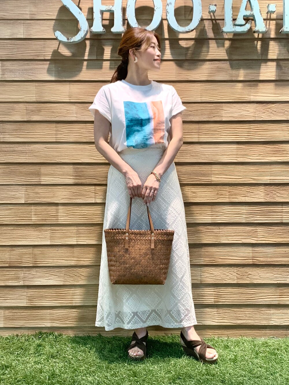 ホワイト系のTシャツ/カットソー、ホワイト系のスカート、ブラウン系のトートバッグを着用したレディースの夏コーディネートの3枚目の写真