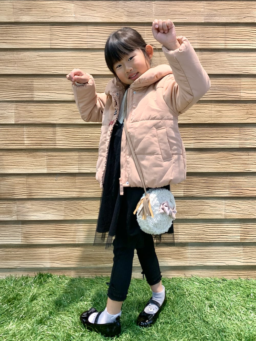 ピンク系のダウンジャケット/コート、ベージュ系のワンピース、ブラック系のその他パンツを着用したキッズの冬コーディネートの5枚目の写真
