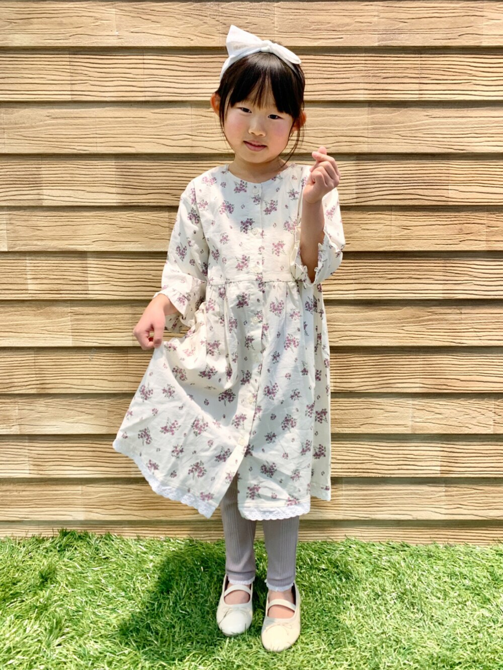 ベージュ系のワンピース、ブラウン系のその他パンツ、グリーン系のラッピングキットを着用したキッズの春コーディネートの2枚目の写真