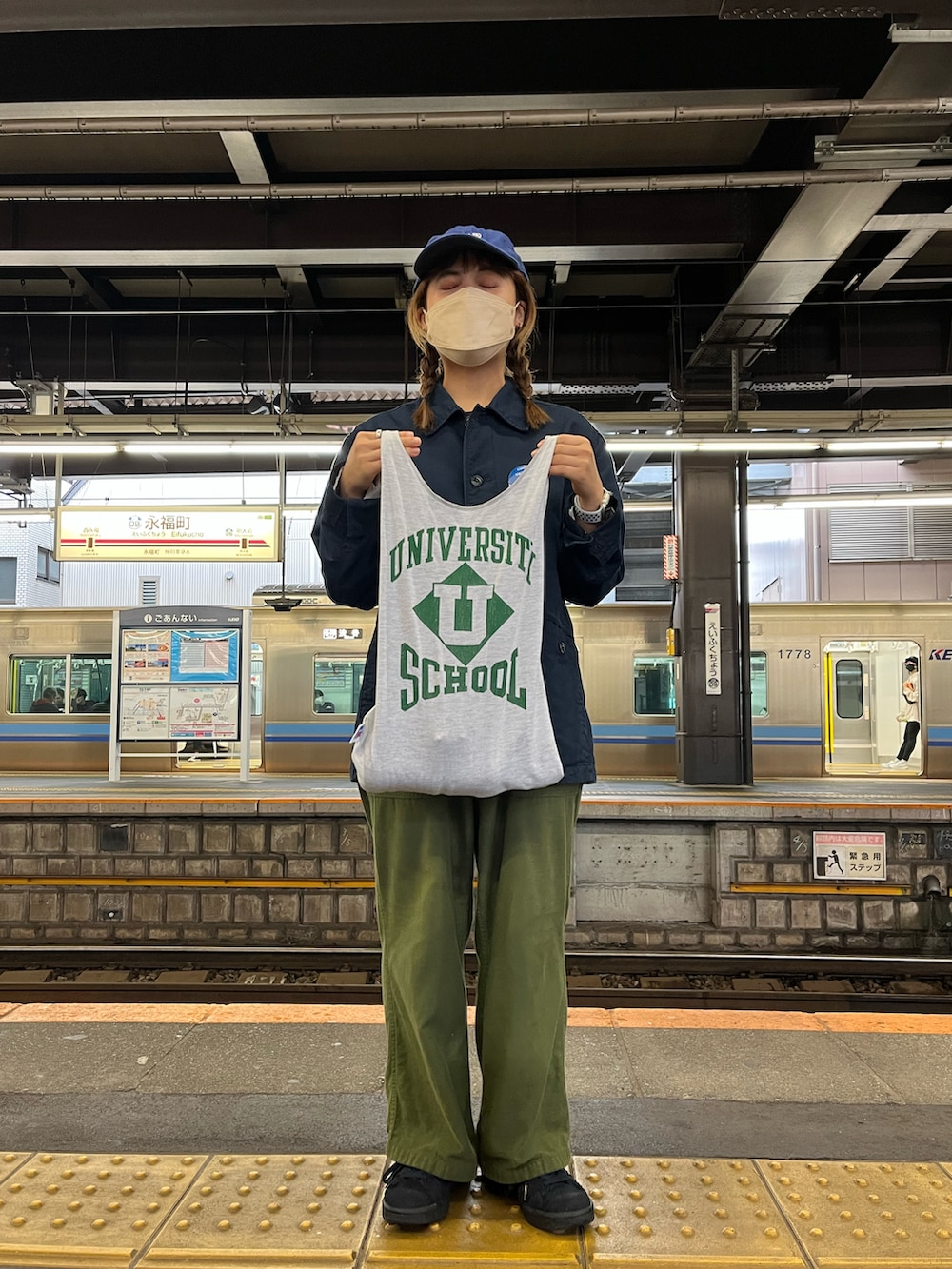 ブルー系のカバーオール、グリーン系のチノパンツ、ブルー系のスニーカーを着用したレディースの春コーディネートの2枚目の写真