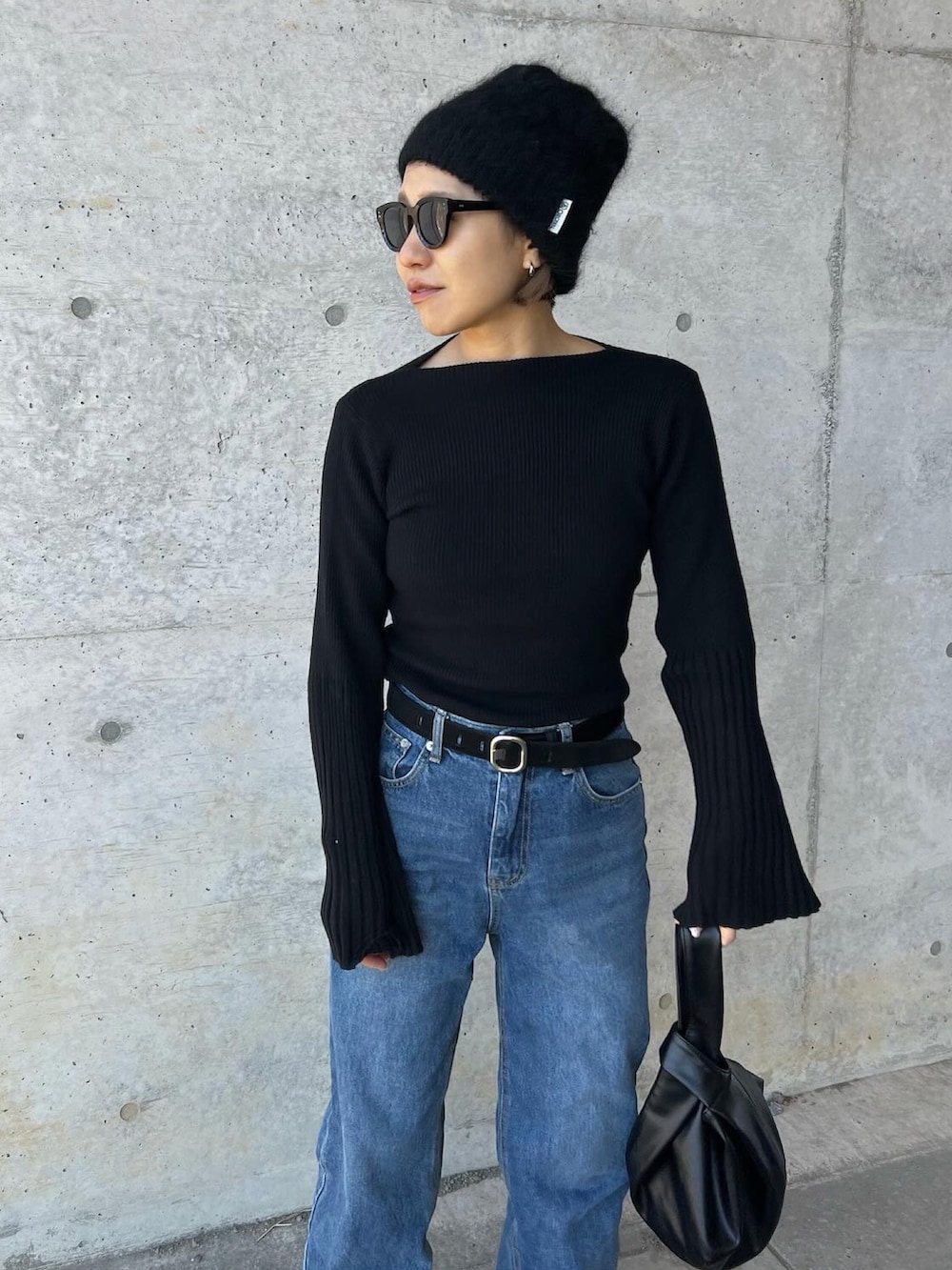 ブラック系のニット/セーター、ブルー系のデニムパンツ、ブラック系のハンドバッグを着用したレディースの冬コーディネートの2枚目の写真