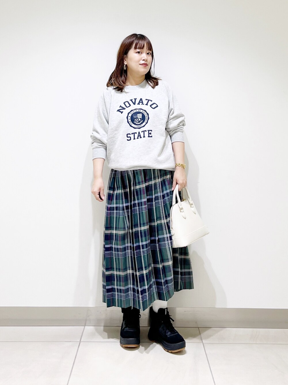 グリーン系のスカート、グレー系のスウェット、ホワイト系のショルダーバッグを着用したレディースの冬コーディネートの7枚目の写真