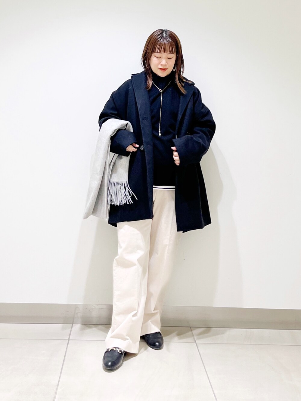 ブルー系のピーコート、ブラック系のニット/セーター、ホワイト系のTシャツ/カットソーを着用したレディースの冬コーディネートの10枚目の写真